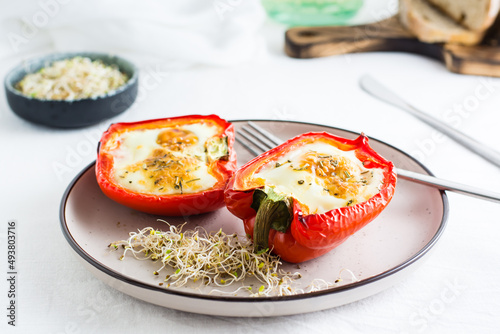 Bell pepper halves baked with egg and microgreens on a plate on the table. Flexitarian organic diet