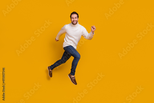 Photo of childish pretty guy dressed white sweater running fast jumping high isolated yellow color background