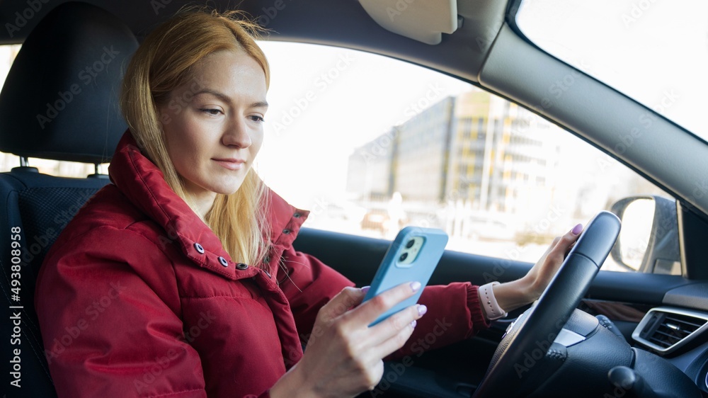 A young beautiful woman is driving a car and typing on her phone A young beautiful woman is driving a car and typing on her phone