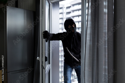 Foto A male thief in a black mask, enters the apartment for robbery, the robber broke