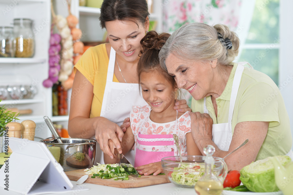 Portrait of happy family coocking salad in kitchen