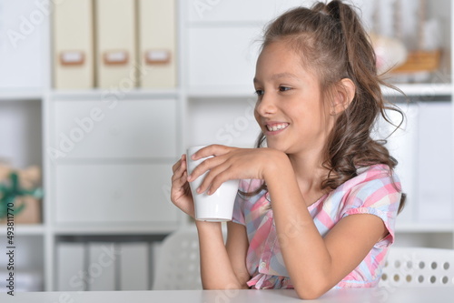 Smiling little girl holding big cup of tea
