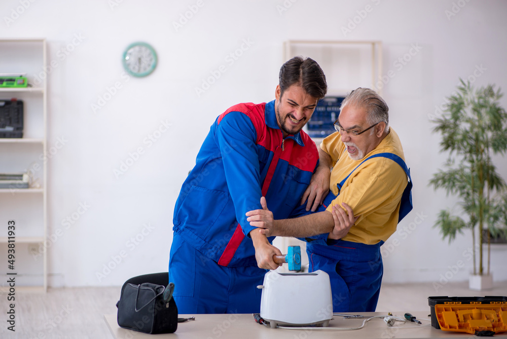 Two male repairmen working at workshop Two male repairmen working at workshop