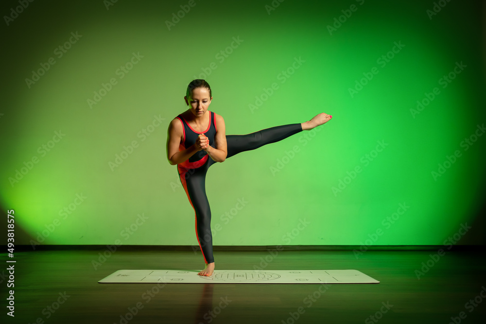 A woman doing yoga exercise on a colored background
