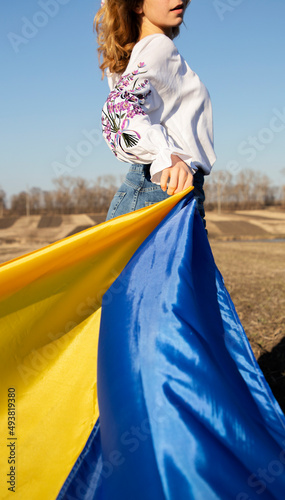 unrecognizable woman wearing traditional embroidered shirt with yellow blue Ukrainian flag. request for help to Ukraine, drawing attention to support Ukrainians in world. Pride of nation, independence