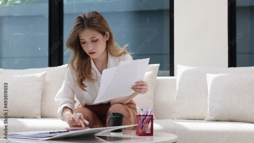 Beautiful young asian woman sitting at living room feeling stressed calculating monthly home expenses, taxes, bank account balance and credit card bills payment, manage budget, accountancy concept. Beautiful young asian woman sitting at living room feeling stressed calculating monthly home expenses, taxes, bank account balance and credit card bills payment, manage budget, accountancy concept.