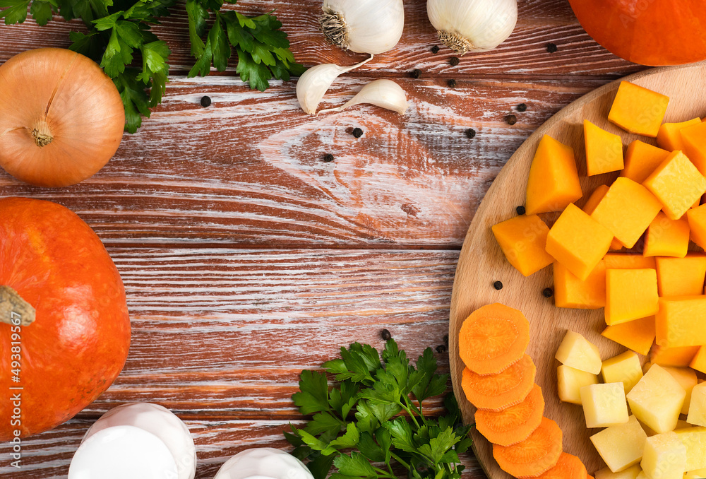 Vegetables for making pumpkin soup on on a wooden kitchen table. Top view. Place for text. Vegetables for making pumpkin soup on on a wooden kitchen table. Top view. Place for text.