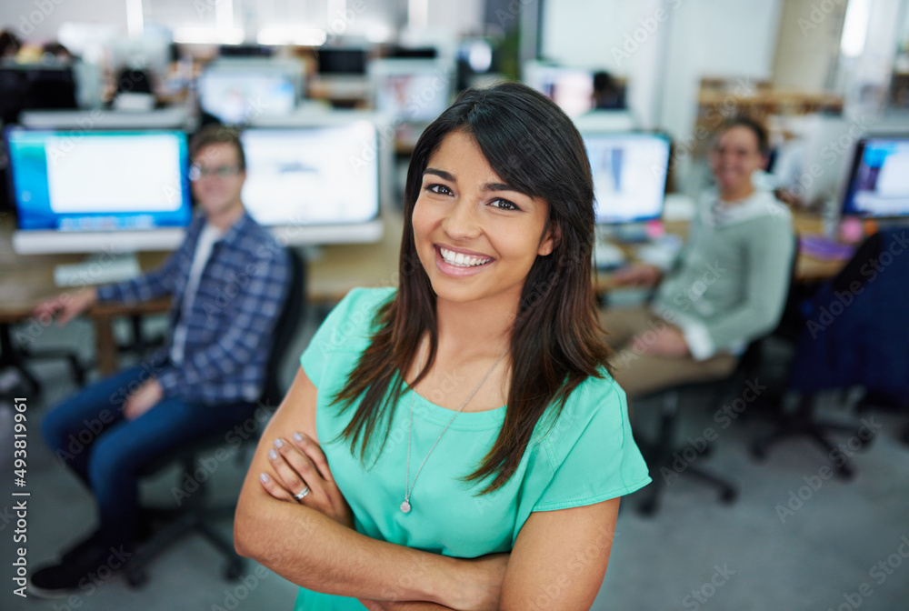 My team is first-class. Portrait of a young woman standing in an office with designers in the background. My team is first-class. Portrait of a young woman standing in an office with designers in the background.