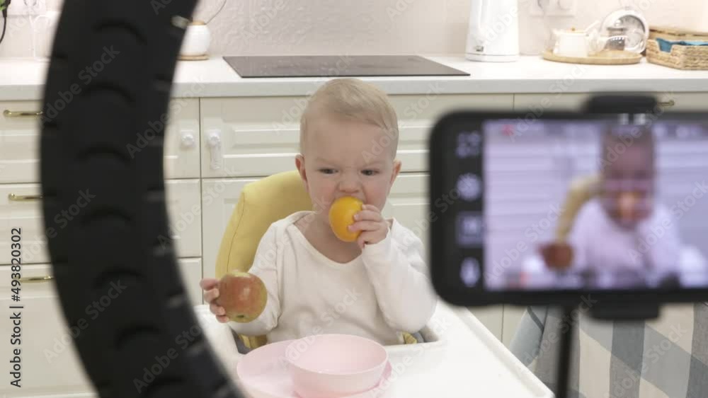 Recording video of kid on mobile phone with ring light, record photo video on smartphone of one-year-old baby boy with fruit. High quality 4k footage Recording video of kid on mobile phone with ring light, record photo video on smartphone of one-year-old baby boy with fruit. High quality 4k footage