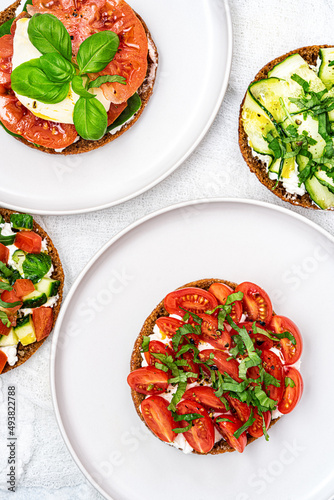 Sandwiches with tomatoes,cucumber,mozzarella,feta and herbs served on white plates. aflat lay. Healthy food concept.