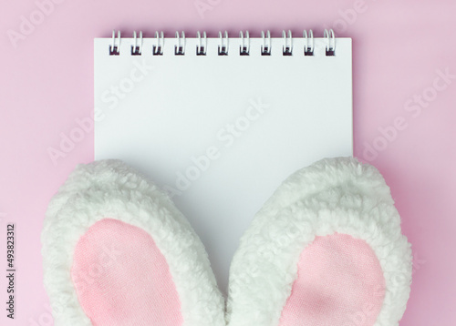 Easter hat bunny ears on pink background on the notebook with copyspace