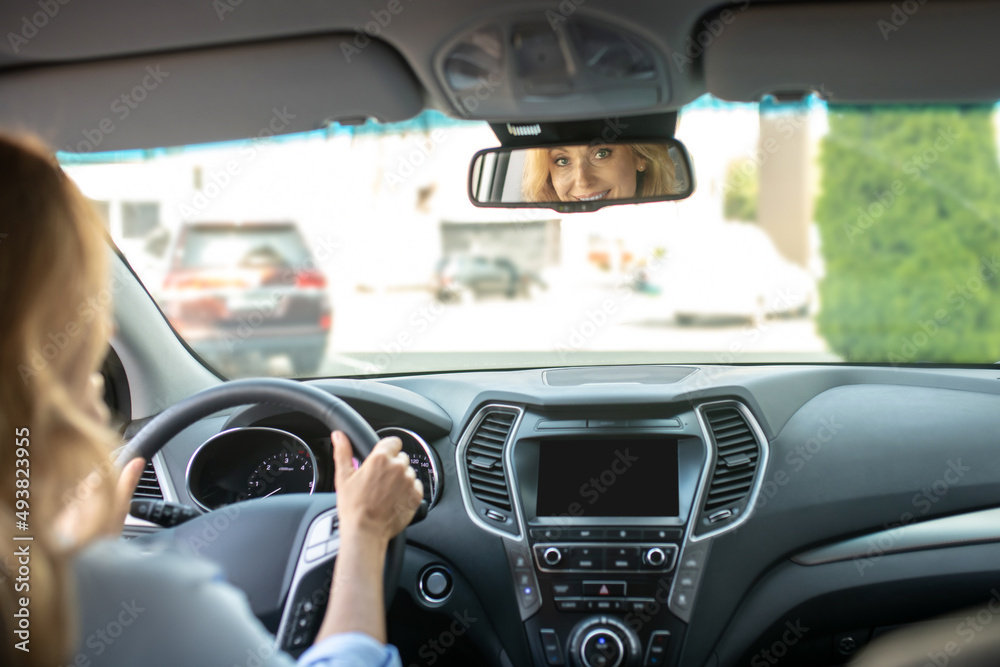 Woman driving car looking in rearview mirror