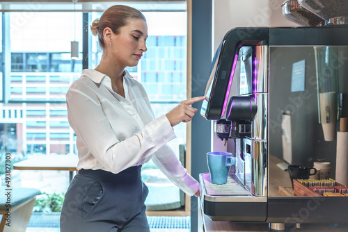 Фотография Businesswoman making drink in coffee machine in office