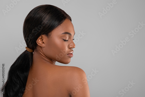 Beauty Care. Calm Black Woman With Bare Shoulders Standing Over Grey Background