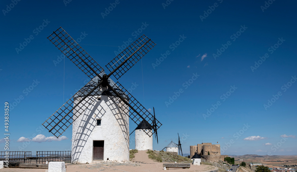 Windmills and old castle in Consuegra, Toledo, Castilla La Mancha, Spain. Several windmills and castle on a hill under a little cloudy sky