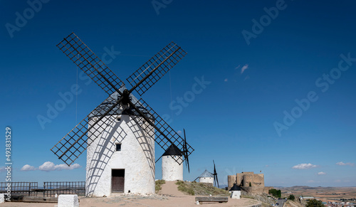 Windmills and old castle in Consuegra, Toledo, Castilla La Mancha, Spain. Several windmills and castle on a hill under a little cloudy sky