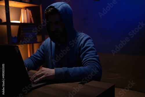 Hacker man working laptop computer. Hacker attack in dark room