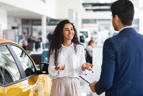 Female customer having conversation with sales associate at auto dealership photo
