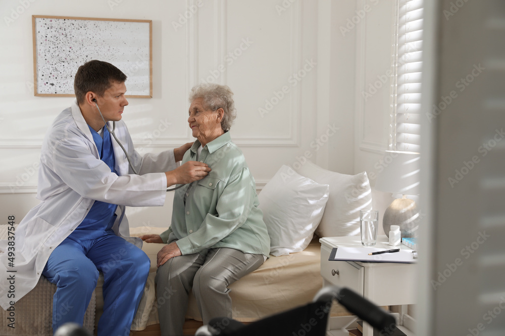 Caregiver examining senior woman in room. Home health care service Caregiver examining senior woman in room. Home health care service