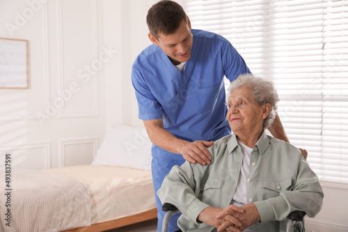 Caregiver assisting senior woman in wheelchair indoors. Home health care service © New Africa