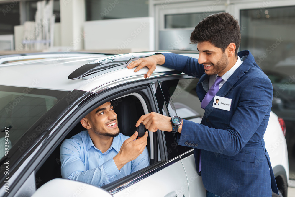Cheerful sales manager giviing car key to owner