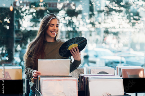 Woman holding vinyl while choosing record in a music shop.
