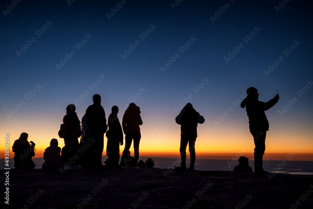 Fototapeta premium Silhouette of unidentified people at the top of mountain waiting for sunrise