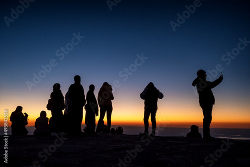 Silhouette of unidentified people at the top of mountain waiting for sunrise