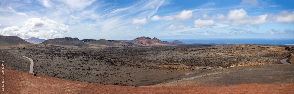 Panoramic view of dormant volcanoes in Timanfaya Nationl Park from Islote de Hilario in Lanzarote, Spain on 9 March 2022