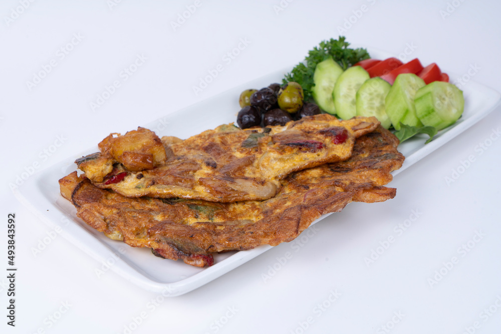 Cropped view of onion omelet with salad, olives and vegetables on white plate, shot in isolated area, gray background, with selective focus from opposite angle. Cropped view of onion omelet with salad, olives and vegetables on white plate, shot in isolated area, gray background, with selective focus from opposite angle.