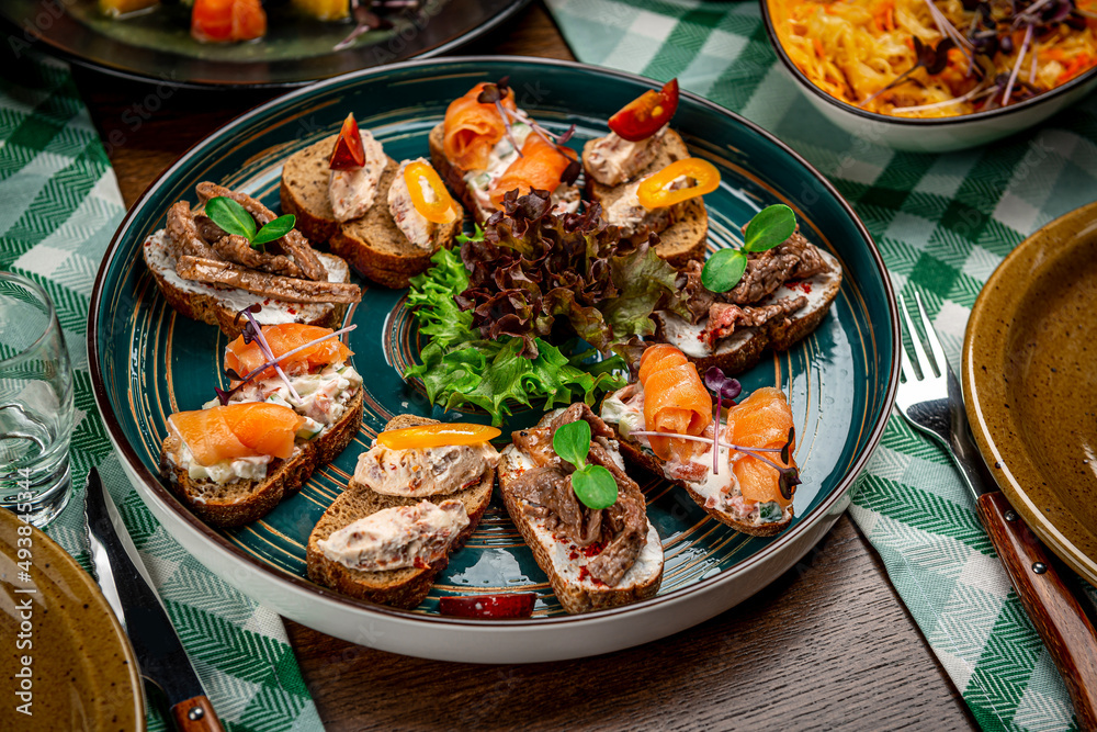 Set of bruschetta with roast beef, shrimps and salmon on dark wooden background