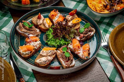Set of bruschetta with roast beef, shrimps and salmon on dark wooden background