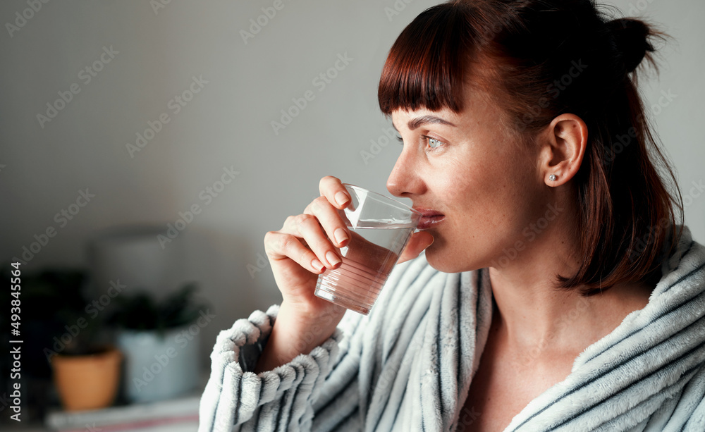 Hydration is a priority to her. Cropped shot of an attractive young woman drinking water in her bedroom at home. Hydration is a priority to her. Cropped shot of an attractive young woman drinking water in her bedroom at home.