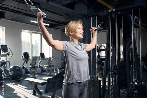 Joyful woman using gym trainer in fitness center