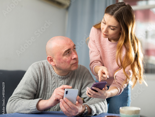 Wife talking with her husband about smartphone trouble at home.