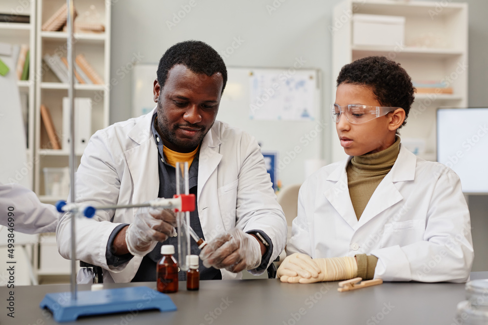 Portrait of African American teacher demonstrating science experiments in school chemistry lab Portrait of African American teacher demonstrating science experiments in school chemistry lab
