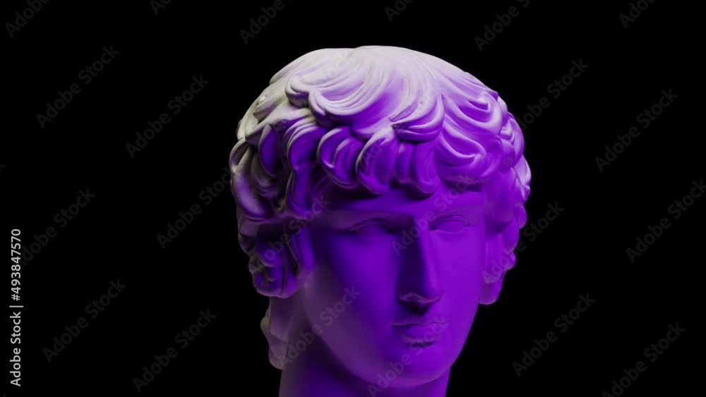 Plaster head sculpture Apollonian in purple neon light close-up. Gypsum ancient statue isolated on black background. Plaster head sculpture Apollonian in purple neon light close-up. Gypsum ancient statue isolated on black background.