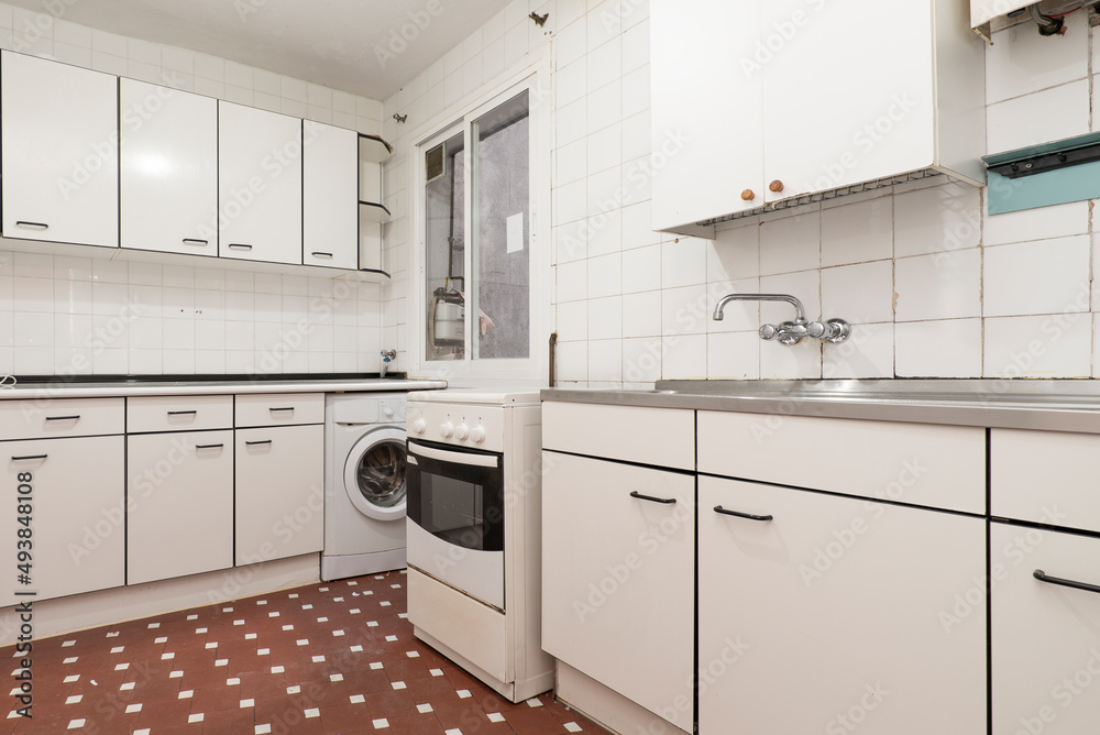 Kitchen with drawer furniture in white tones with details and edges in black with a metal kitchen, stainless steel sink and white square tiles with a clay terrazzo floor with white touches Kitchen with drawer furniture in white tones with details and edges in black with a metal kitchen, stainless steel sink and white square tiles with a clay terrazzo floor with white touches
