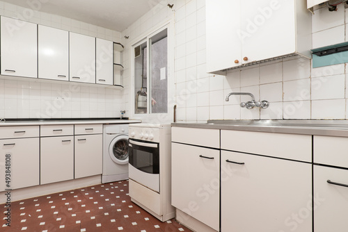 Kitchen with drawer furniture in white tones with details and edges in black with a metal kitchen, stainless steel sink and white square tiles with a clay terrazzo floor with white touches