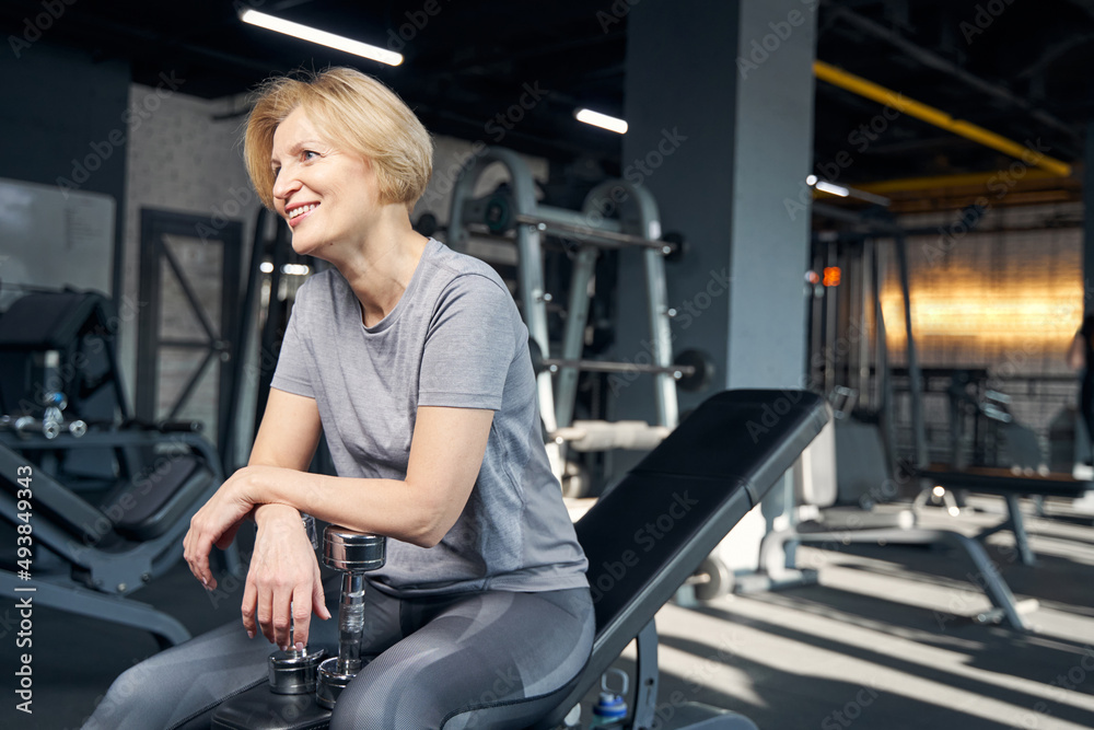 Cheerful woman resting after workout in gym Cheerful woman resting after workout in gym