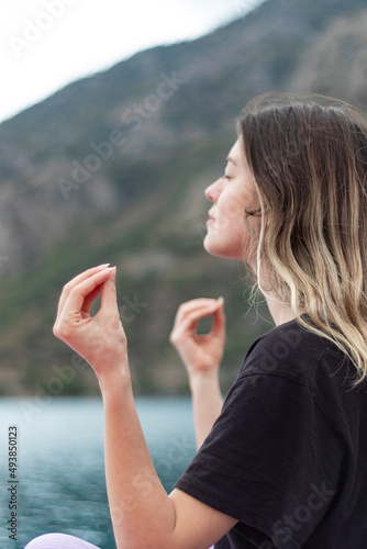 Close up photo of doing meditation young girl. Peace, and mindfulness. Sea background. Beautiful landscape. Vertical photo.
