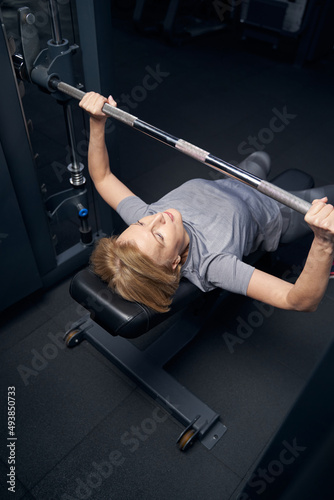 Woman using barbell press bench machine during workout