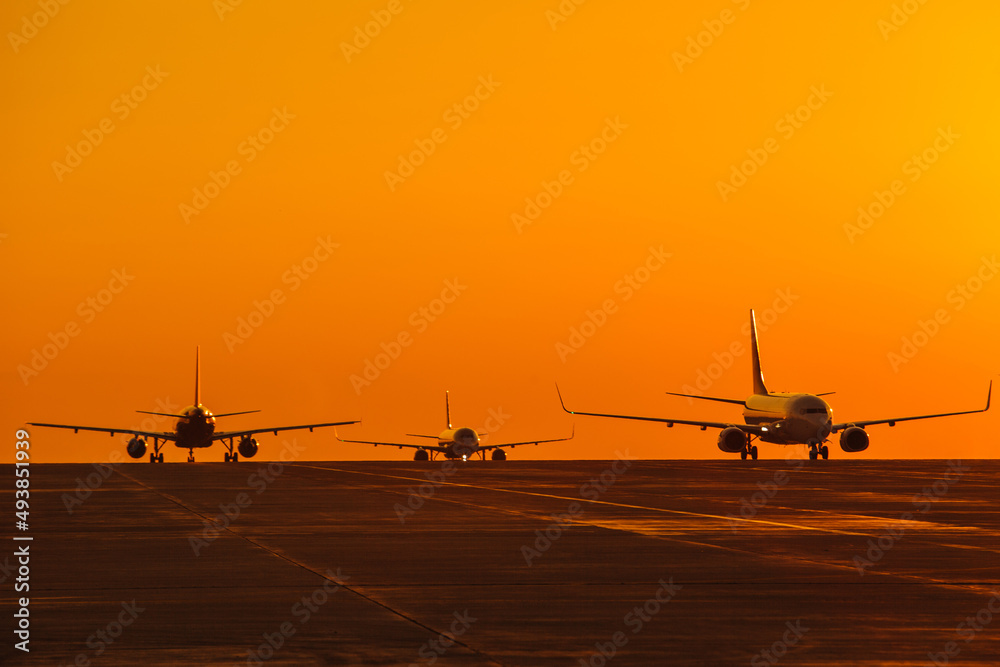 Landing airplanes against colorful sky at sunset. Travel background with passenger plane. Evacuation Landing airplanes against colorful sky at sunset. Travel background with passenger plane. Evacuation