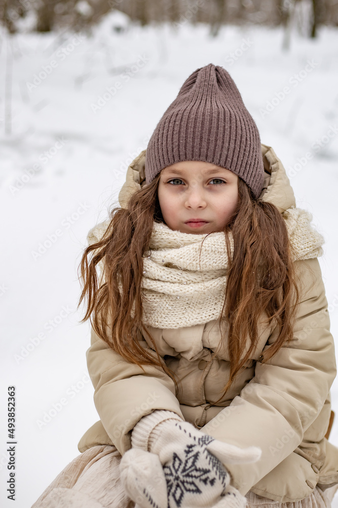 large portrait of a cute blonde girl in a warm hat in winter