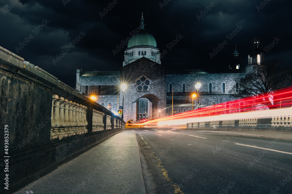 Night scenery with Galway cathedral and car light trails passing by in Ireland 