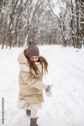 a cute six-year-old girl runs along the road in a snowy forest