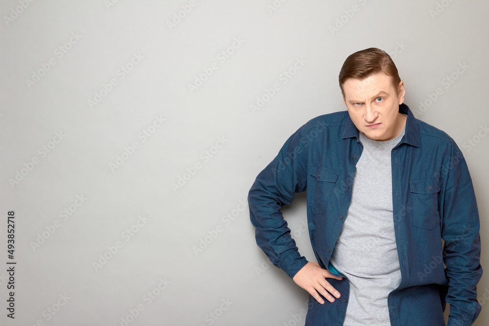 Portrait of disgruntled mature man holding hand on hip Portrait of disgruntled mature man holding hand on hip