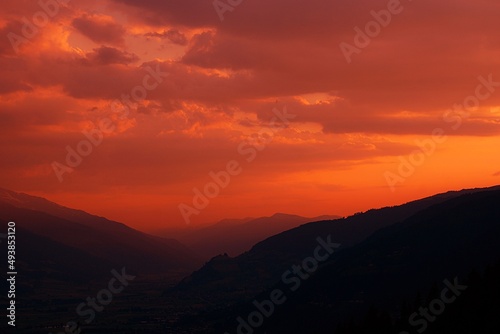 Red sky during sunset with clouds and mountains.