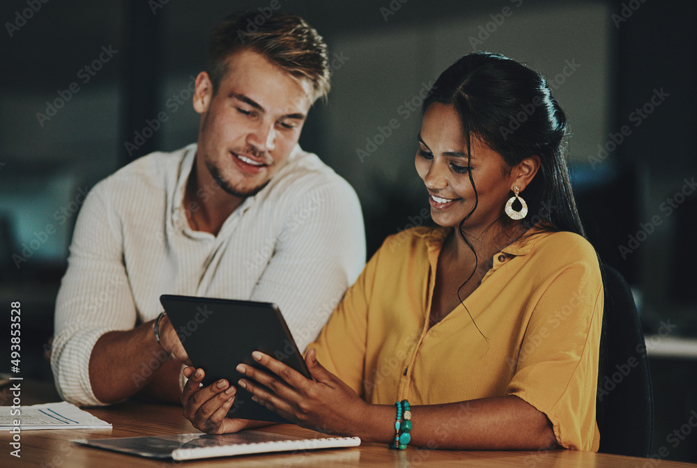 The world online will enable them to beat the deadline. Shot of two businesspeople using a digital tablet together in an office at night. The world online will enable them to beat the deadline. Shot of two businesspeople using a digital tablet together in an office at night.