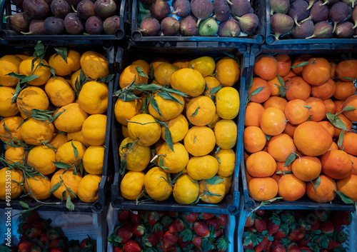 Fresh tangerines  strawberries and figs on the store counter. Colorful fruits are sold at the street market. Citruses and berries in plastic boxes